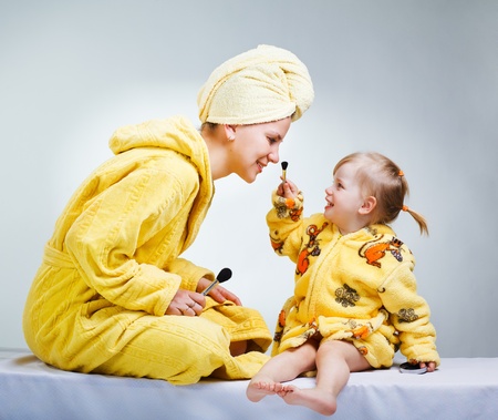 Daughter and mother putting makeup after bathroomの写真素材