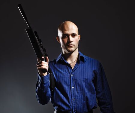 Portrait of a handsome young man holding a gun.