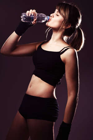 sports woman drinks water in studioの写真素材