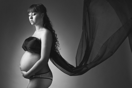 Beauty and sexy of young pregnant woman with blowing dark material - grey backgroundの写真素材