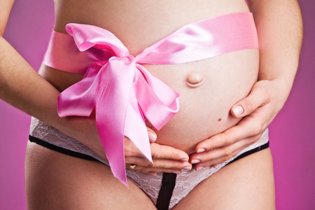 Pregnant belly with pink ribbon . Third trimester.の写真素材