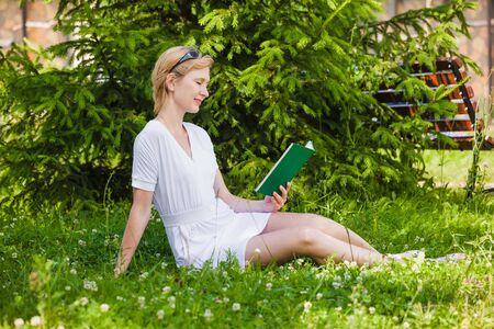 Young woman reading a book in the parkの写真素材