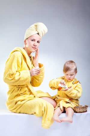 Daughter and mother putting makeup after bathroomの写真素材