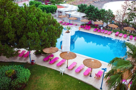 Sunbeds and parasols on wooden deck nearby swimming pool. The luxury outdoor recreation for tourist.の写真素材