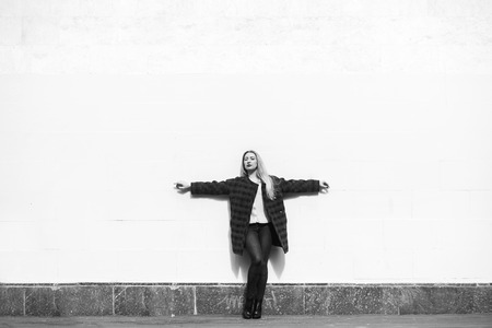 Beautiful blonde woman standing by a stone wallの写真素材