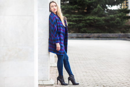 Beautiful blonde woman standing by a stone wallの写真素材