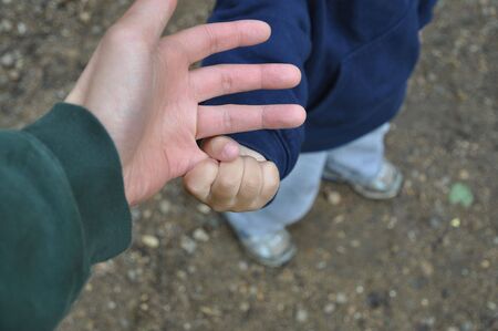 Sharp focus on a toddler's hand grasping father's pinkyの写真素材