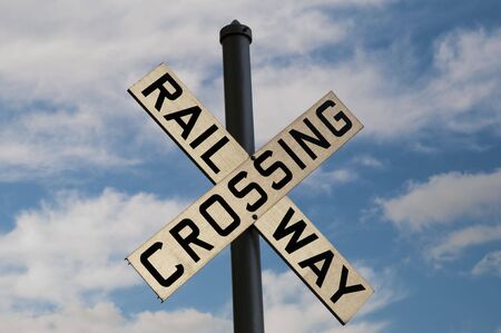 Railway Crossing sign with bright blue sky behind itの写真素材