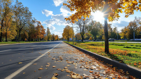 A serene autumn scene showcasing a road lined with vibrant trees and fallen leaves under a bright blue sky, inviting peaceful moments in nature.の素材