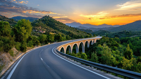 Capture the tranquility of a winding road with a stunning stone bridge under a vibrant sunset. This serene landscape evokes the essence of adventure and beauty.の素材