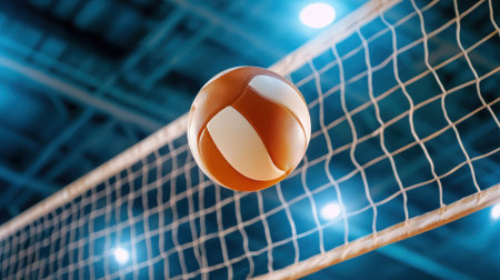 A vibrant volleyball captured in mid-air over a net during an exciting indoor game. This image showcases the energy and action of sports, perfect for promoting athletic events or recreational activities.の素材