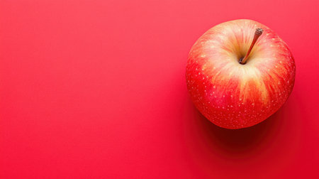 A vibrant red apple resting on a bold red background, showcasing its freshness and appeal. Perfect for health, nutrition, and food-themed projects.の素材
