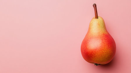 This image showcases a ripe pear resting on a soft pink background, emphasizing the natural beauty of fresh fruit. Perfect for healthy eating concepts.の素材