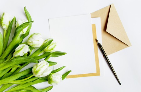 Letter, envelope and bunch of fresh tulips on white background. Vintage wedding invitation card or...