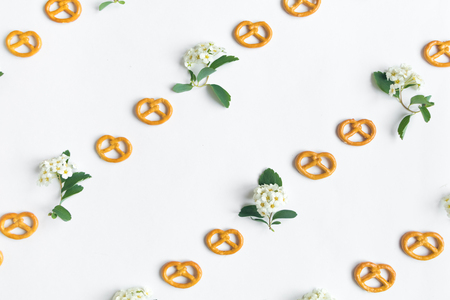 Minimalistic diagonal cookies pretzels and spirea arguta flowers pattern on white background. Flat lay, top view, diagonal lines patternの写真素材