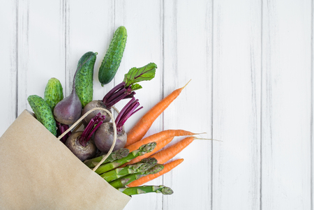 Paper shopping bag with fresh bread, carrots, cucumbers, asparagus and beet. Eco shopping concept, products for cookingの写真素材