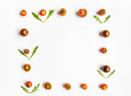 Cherry tomatoes and rocket salad leaves square frame on white background. Healthy food for salad. Flat lay, top view, view from above with place for your textの写真素材