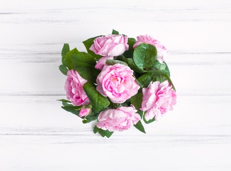 Pink rose flowers in a vase against white vintage wooden table. Cozy natural composition. Enjoying nature beauty. Flat lay, top viewの写真素材