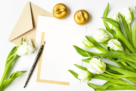 Letter, envelope and bunch of fresh tulips on white background. Vintage wedding invitation card or love letter with white flowers. Romantic or holiday concept, top view, flat lay, overhead viewの写真素材