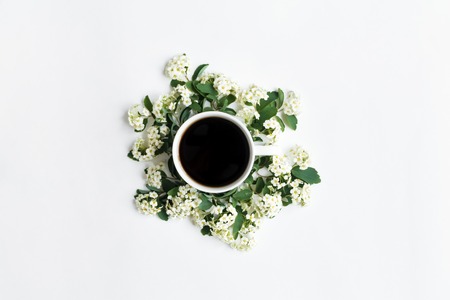 Cup of black coffee and beautiful white flowering Spirea arguta (brides plant) branches on white table. Flat lay, top view. Romantic patternの写真素材
