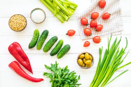 Ingredients for healthy lunch with herbs and vegetables, bright background. Tomatos, cucumbers, onions, celery, sweet pepper, rocket salad, salt, pine nuts and olives. Flat lay, view from aboveの写真素材
