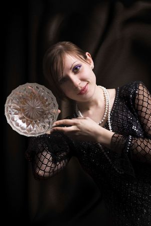 The slender and elegant woman in black dress, shows dish from glassの写真素材