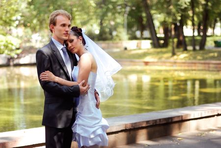 Young bride and groom embracing, standing in a park on a beautiful sunny dayの写真素材