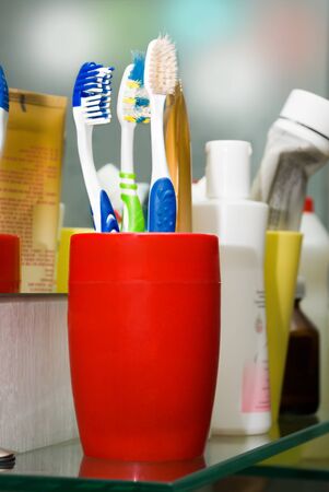 Three colorful toothbrushes in a glass in the bathroom.の写真素材