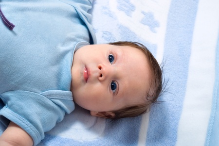 Portrait of a little baby lying on a bed with blue eyes