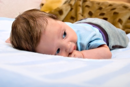Little child baby portrait. Cheerful baby lies on stomach.の写真素材