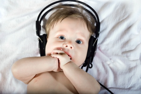 Portrait of beautiful baby listening to music on headphones.の写真素材