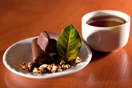 Cup of tea and saucer with sweet dessert of chocolate snacks.の写真素材