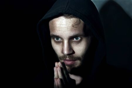 Low key portrait young man praying on the dark background.の写真素材