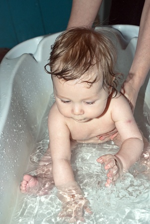 Bathing a cute little baby in the bath.
