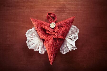 Red heart with white wings on wood background 