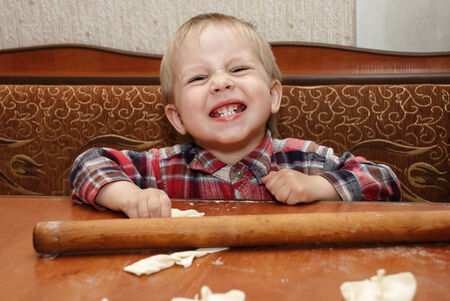 Little funny boy in the kitchen engaged in cookingの写真素材