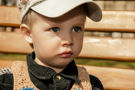Portrait of little boy in cap outdoors.の写真素材
