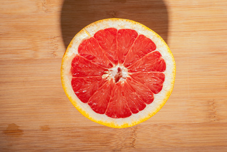 Slices of ripe red grapefruit on wooden board.の写真素材