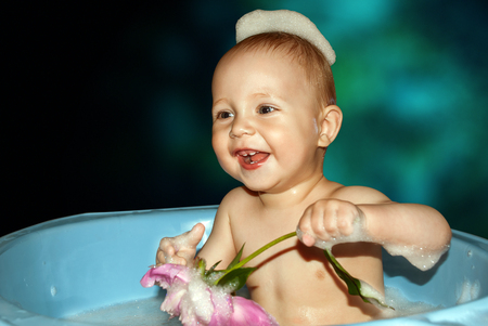 Little boy in bath with flower in hand on blue background.の写真素材