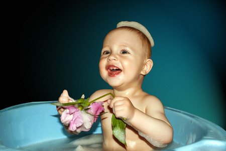 Little boy in bath with flower in hand on blue background.の写真素材