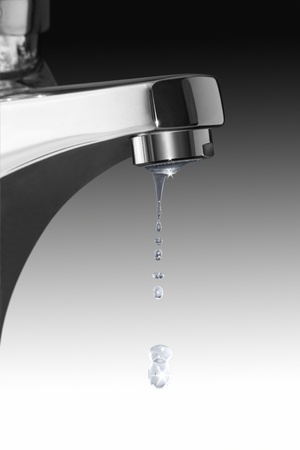 detail of a dripping chrome faucet and some water drops in gradient backの写真素材