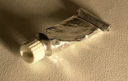 studio photography of a warm toned old paint tube partly rolled-up , with clipping pathの写真素材