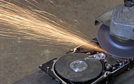 hard disk drive with rotating grinder and sparks in front of rusty back