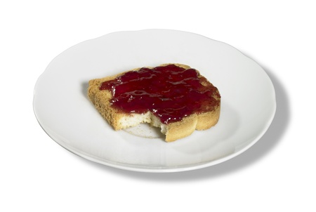 studio photography of a slice of rusk with red jelly on a porcelain plate, isolated on white with clipping pathの写真素材