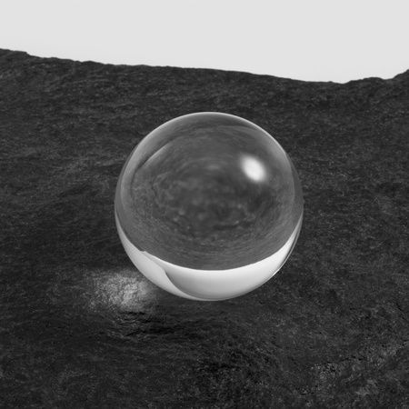 a clear crystal ball on rough dark grey stone surface in front of red back