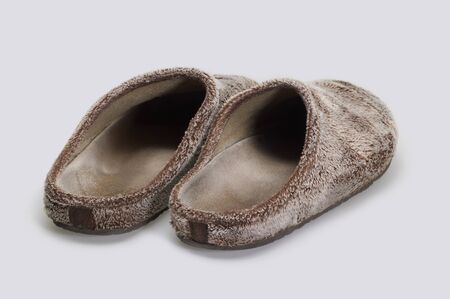 a pair of brown fluffy slippers in light grey back