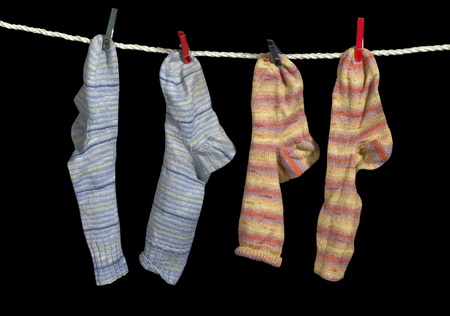 clothesline with some multicolored sox fixed with clothes pins in black backの写真素材