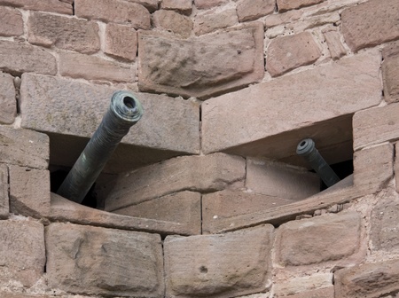 detail of the Haut-Koenigsbourg Castle, a historic castle located in a area named "Alsace" in France, showing two cannons jut out of solid stone wallsの写真素材