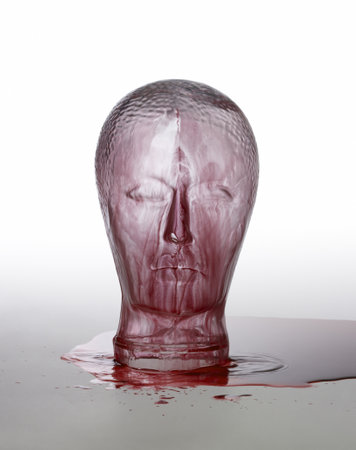 generic human "dummy" head made of glass, overwhelmed with red fluid in light grey backのeditorial素材