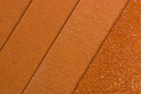 abstract background showing some orange colored sandpaper in various grainsの写真素材